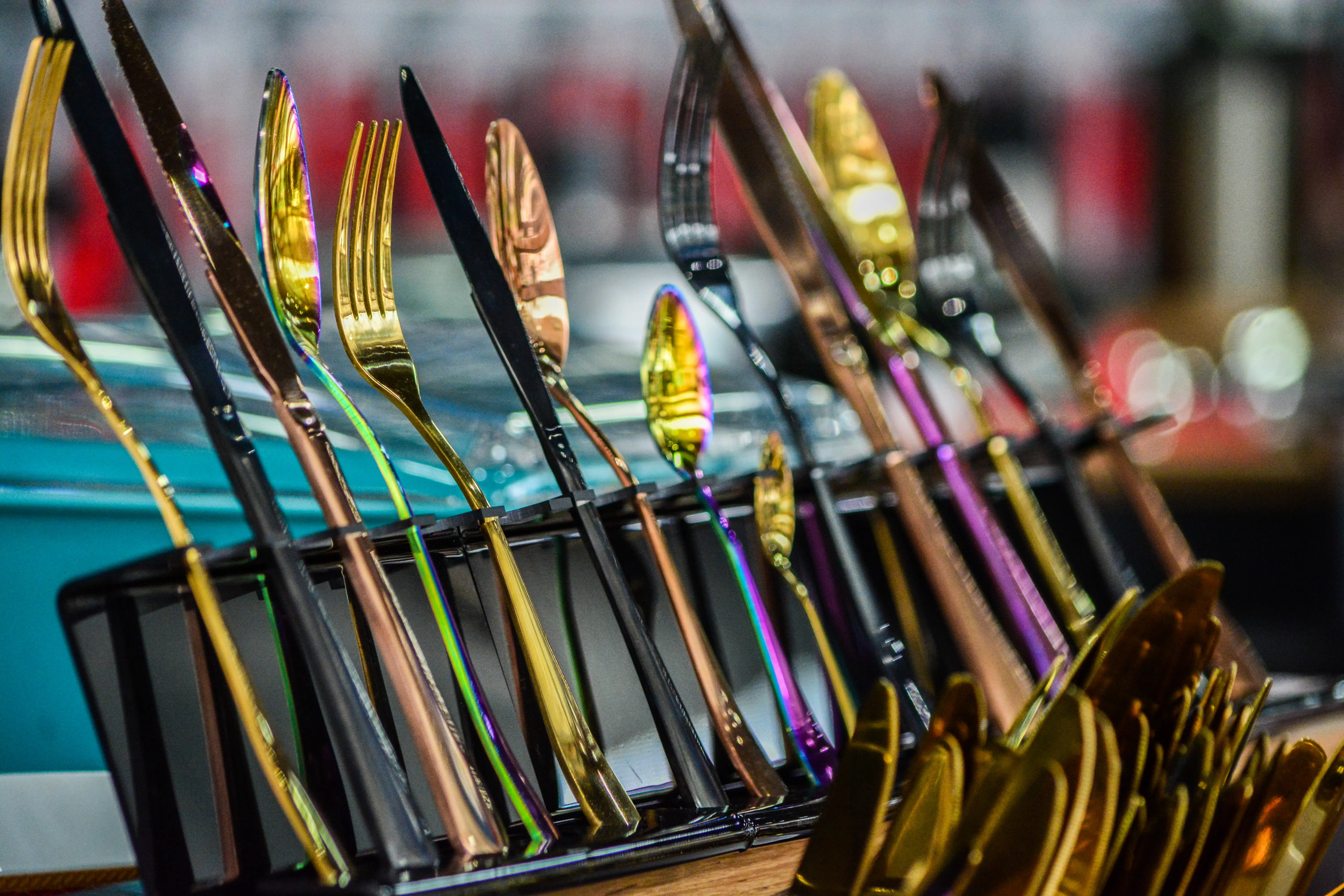 Close-up of multicolored knives, forks, and spoons in a row.